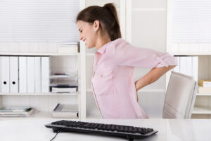 Woman in grimacing holding painful back