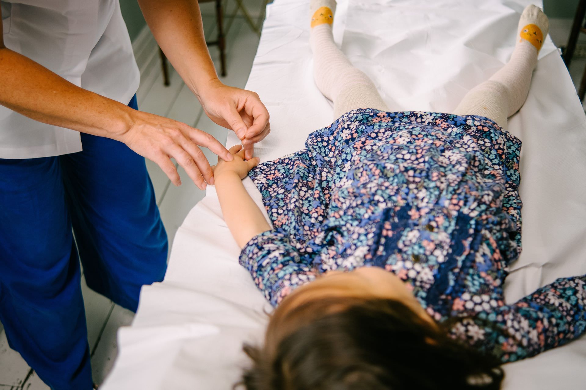 A girl lying on a treatment couch having acupuncture.