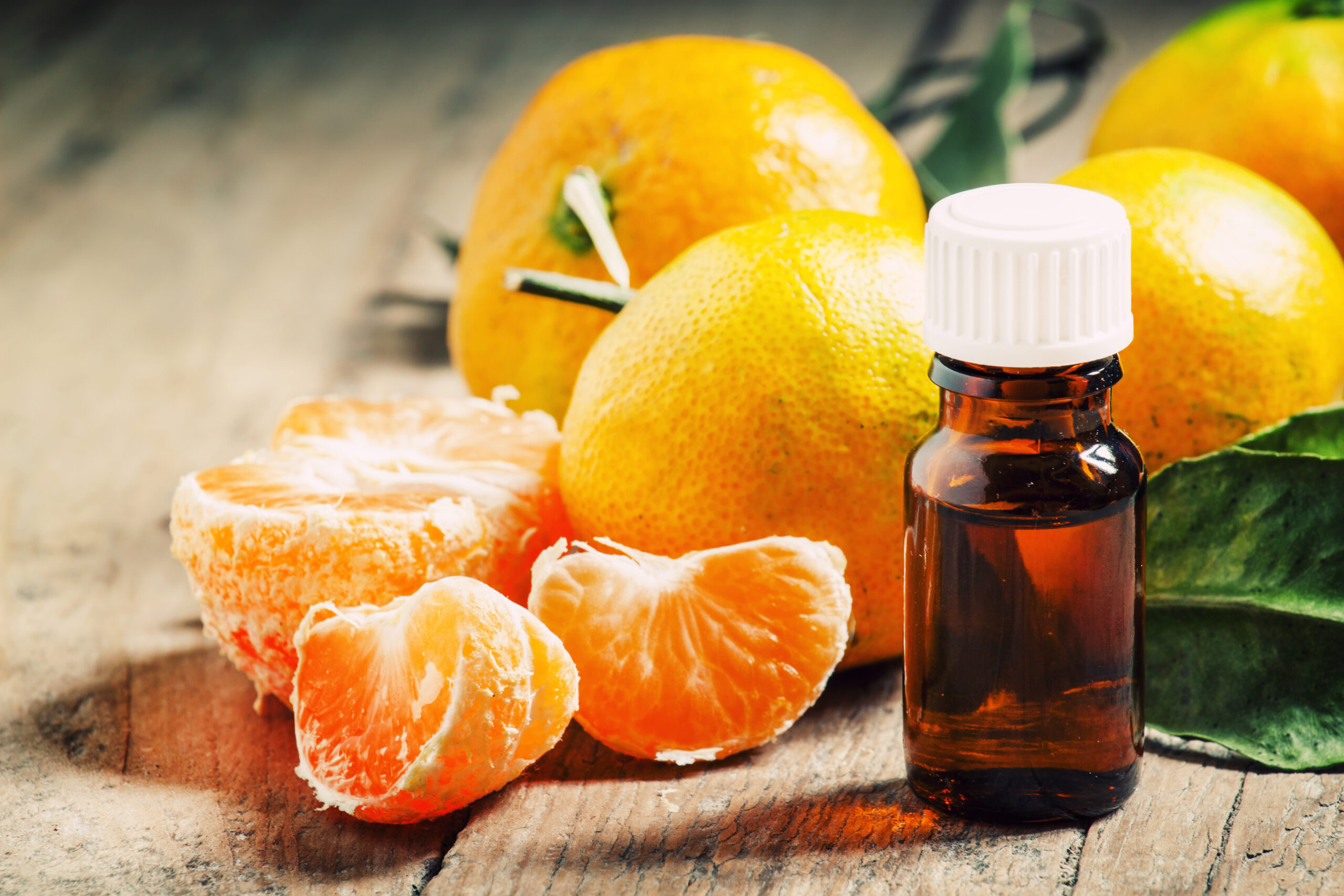 Orange slices next to a bottle of orange aromatherapy massage oil.